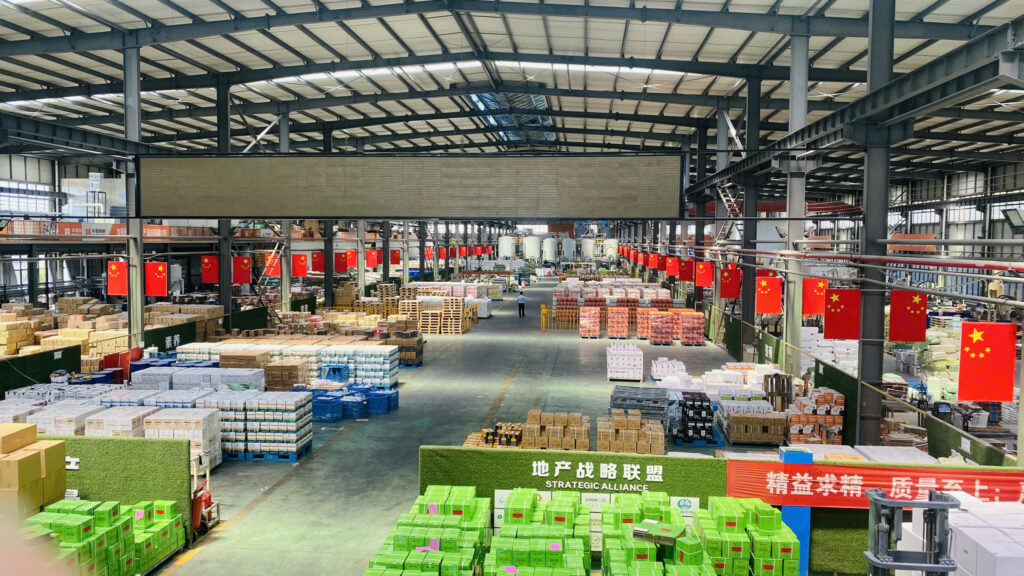 Industrial Warehouse Interior with Stacked Pallets and Red Chinese Flags Along the Aisles Packed Goods Everywhere  Vcc Sealant   Sản Xuất Phân Phối Keo Silicone Và Chất Kết Dính Chuyên Nghiệp