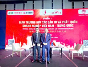 Ảnh chụp hai người đàn ông mặc vest đứng trước màn hình LED đỏ khổng lồ có chữ 'PHIÊN 1' và 'GIAO THƯƠNG HỢP TÁC ĐẦU TƯ...' trong một hội nghị hợp tác doanh nghiệp Việt Nam - Trung Quốc trong khuôn khổ APEC 2026