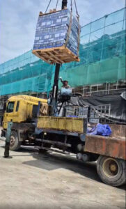 Xe cẩu chuyên dụng đang hạ các pallet keo VCC tại công trường dự án xây dựng lớn.
