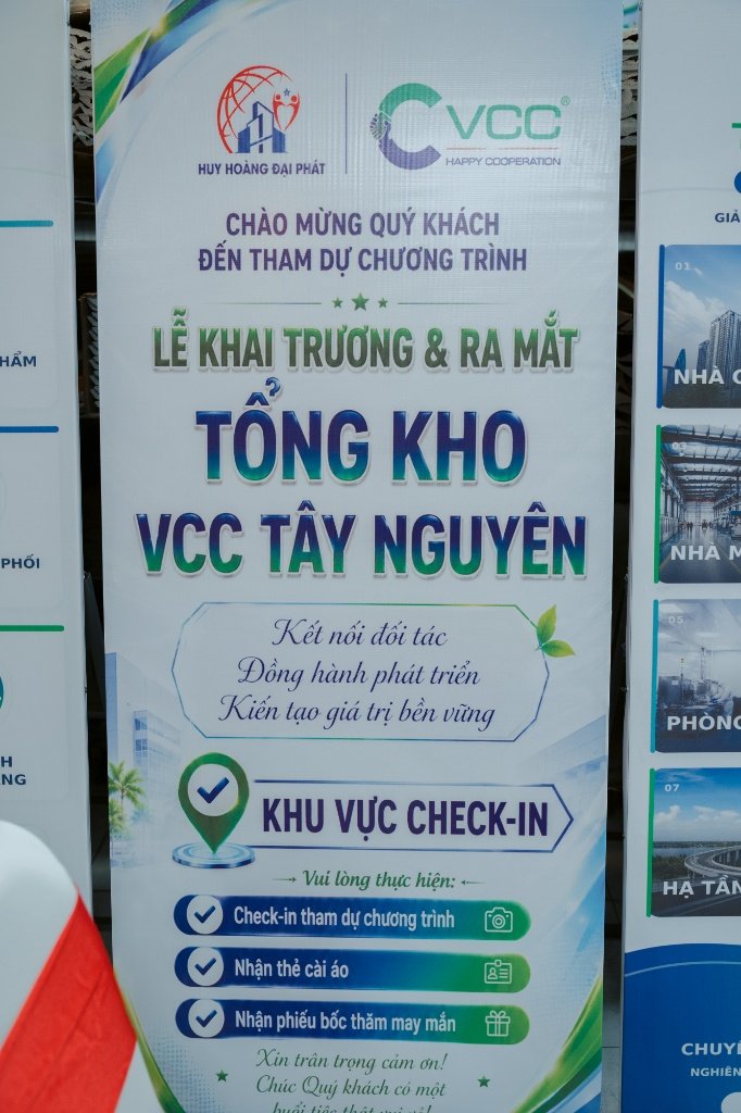 Khu vực check in đón khách tại lễ khai trương tổng kho VCC tại Tây Nguyên – VCC Sealant - Sản xuất, phân phối keo silicone và chất kết dính chuyên nghiệp Vertical Banner with Logos Huy Hoàng Đại Phát and Vcc Vietnamese Text Announcing the Grand Opening of the Vcc Tây Nguyên Warehouse and Check in Area Including Steps Check in Receive Lanyard and Lucky Draw Slips Vcc Sealant Sản Xuất Phân Phối Keo Silicone Và Chất Kết Dính Chuyên Nghiệp